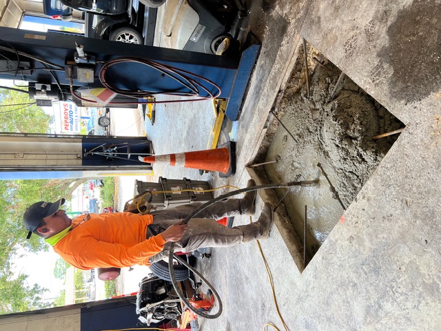 Crew placing concrete in a lift footing under a shop hoist.
