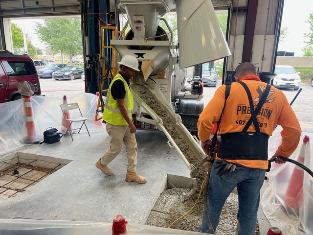 Concrete truck pouring a lift footing inside an automotive shop.