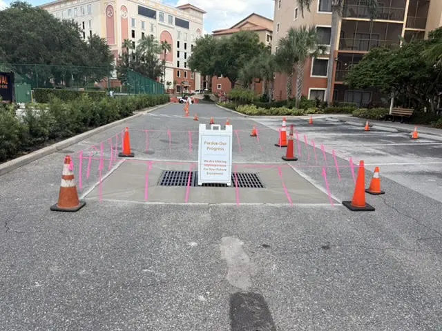 Drain inlet reset in a parking lot, marked off while the concrete cures.