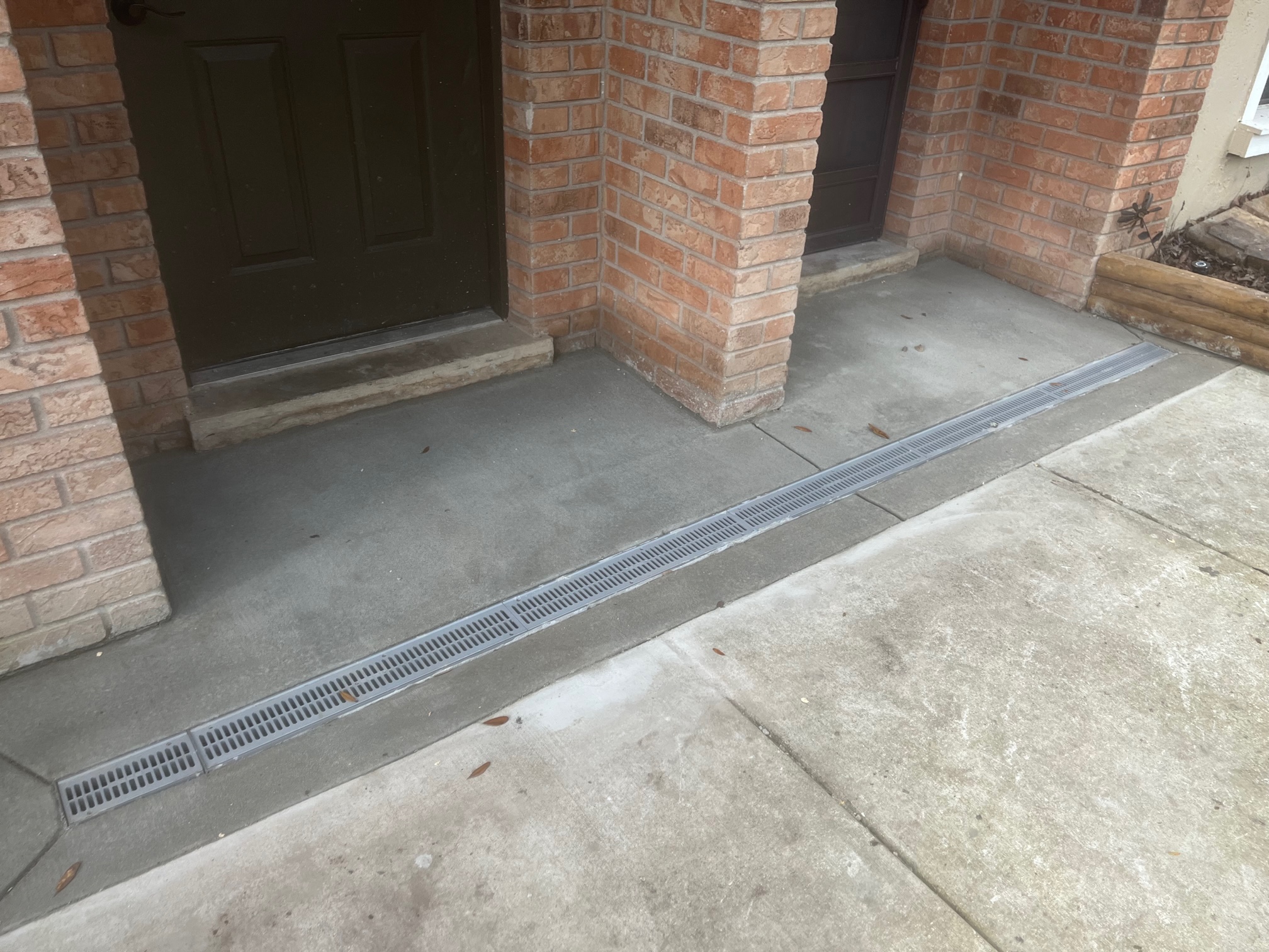 A channel drain set in concrete at a building entry.
