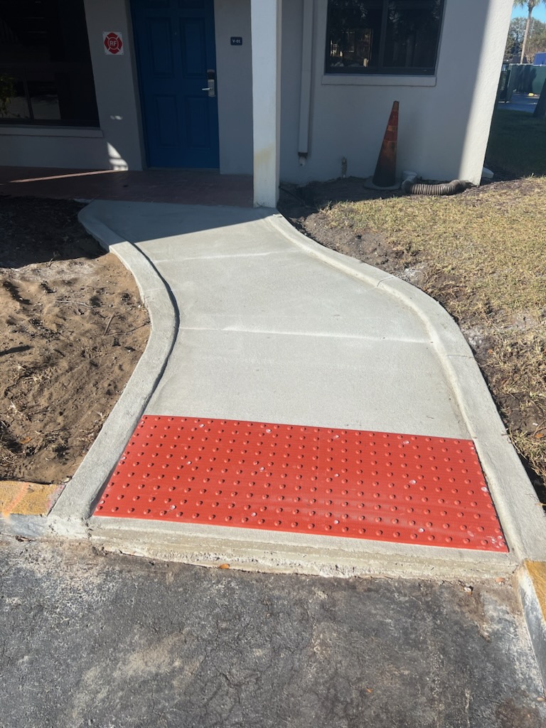 Concrete ramp with a red detectable warning where the walk meets the lane.